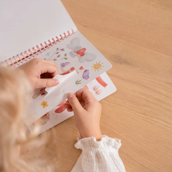 Girl a sheet of stickers over a notebook on a wooden surface