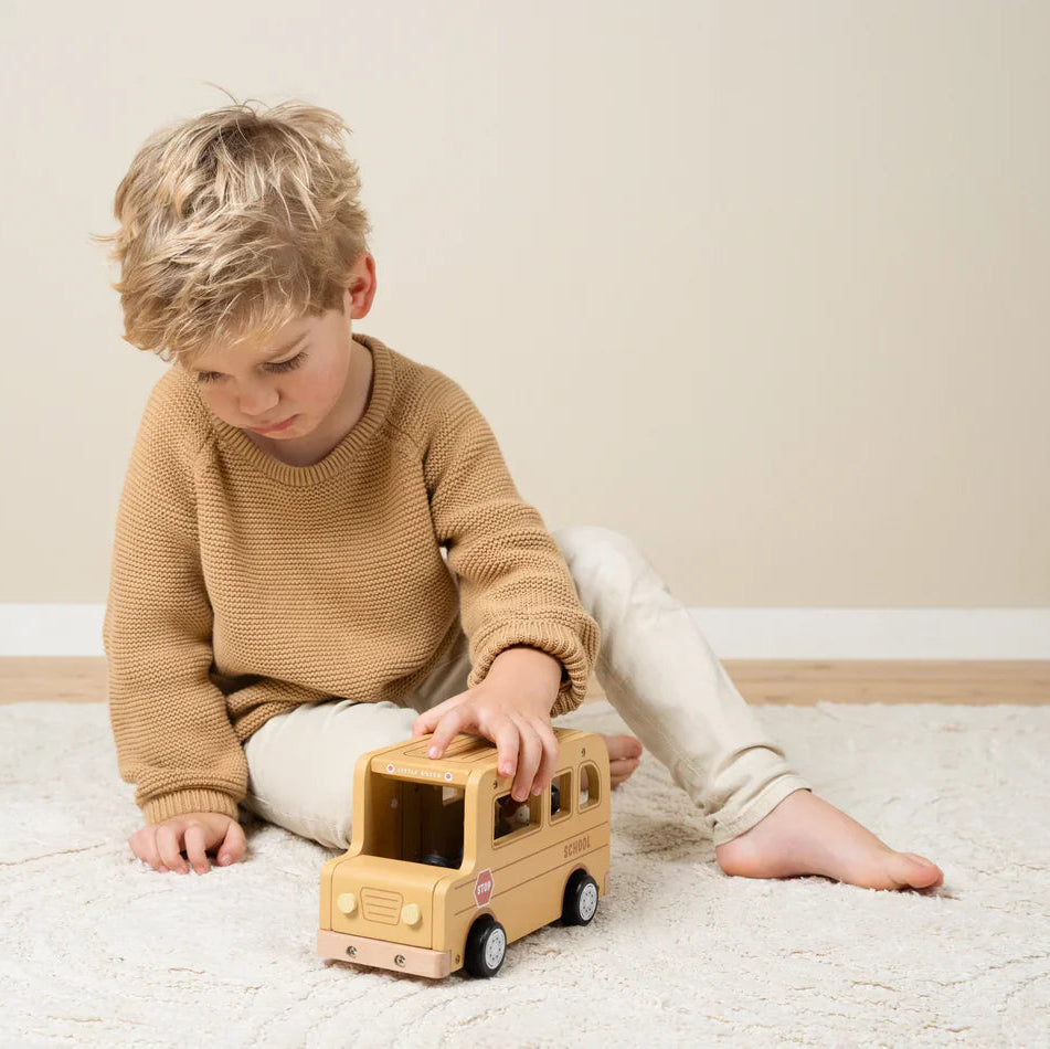Child playing with wooden toy school bus