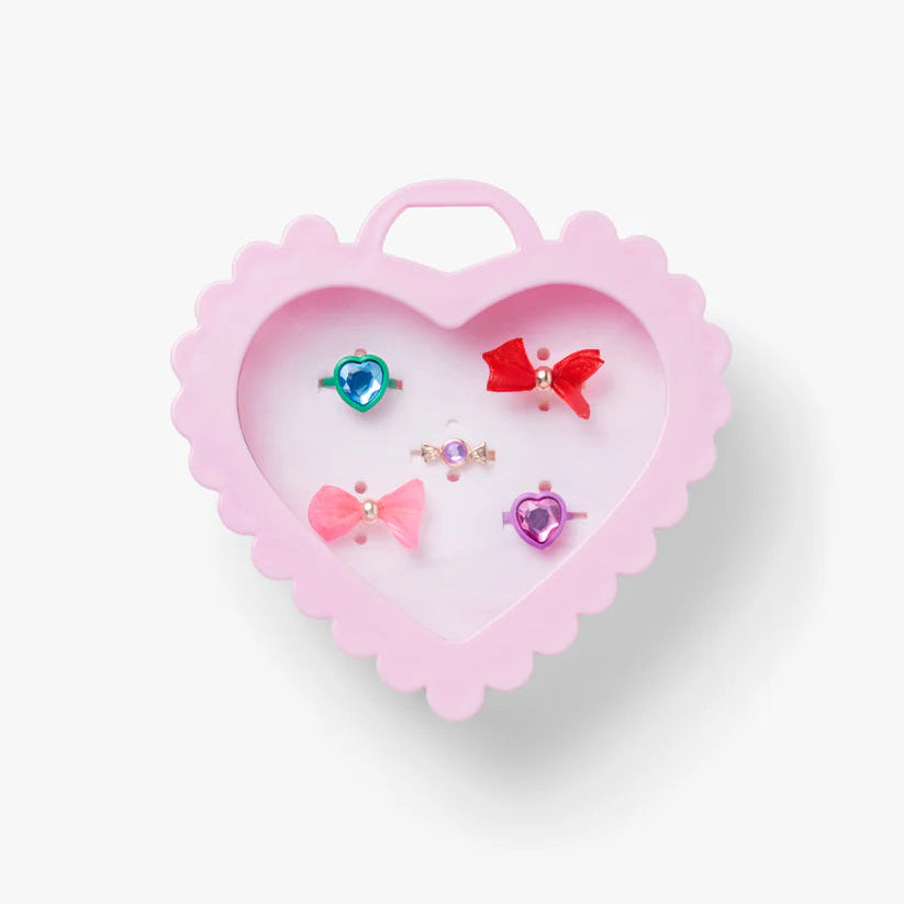 Heart-shaped pink jewelry box with colorful earrings on a white background
